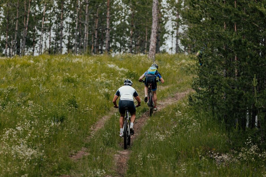 Two mountain bikers on a dirt trail through a forest