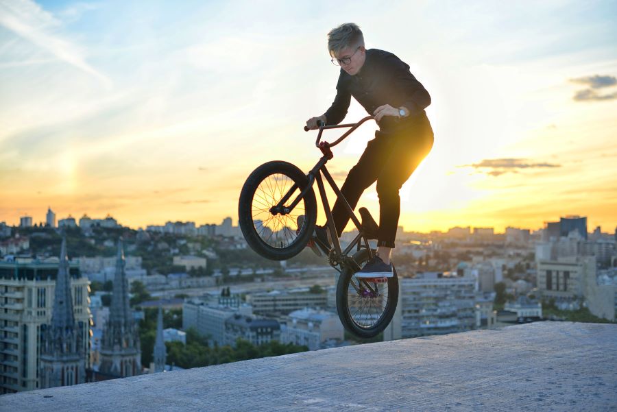 A man performing a BMX trick with a cityscape behind him
