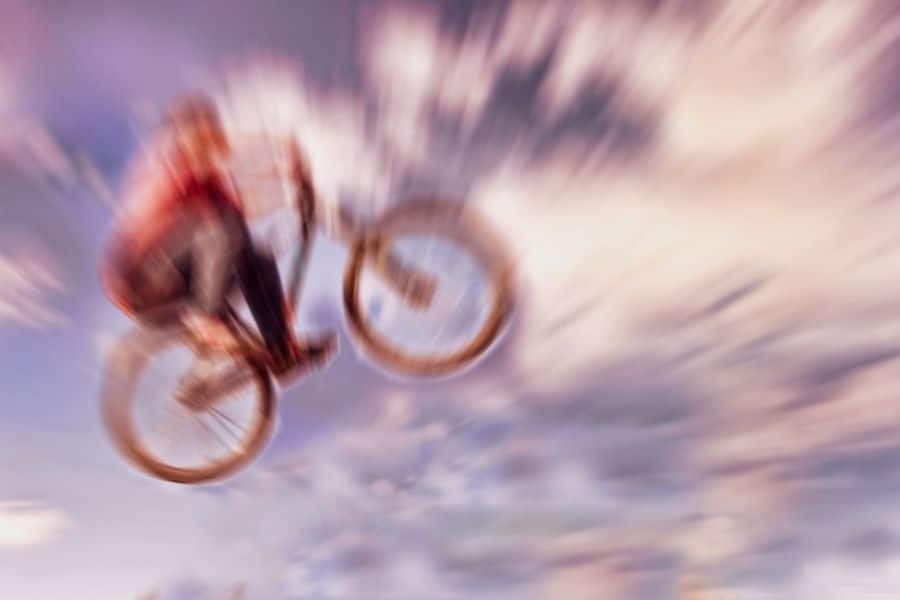 Riding a mountain bike bmx hybrid through air following jump