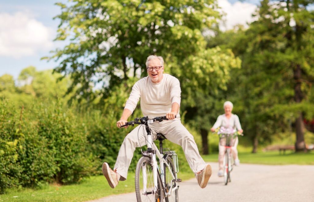 Older man riding bike with feet off pedals